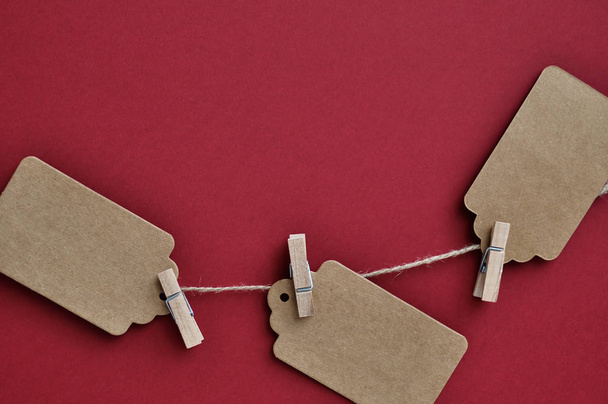 Paper craft discount labels are attached with clothespins to the rope on a red background. - Foto, Imagem