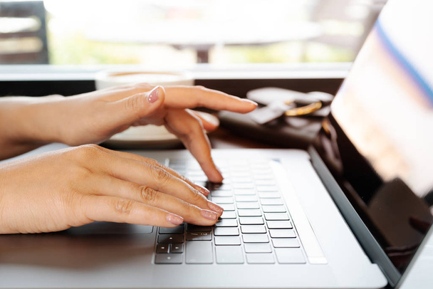 žena rukou psát na klávesnici přenosného počítače. Žena v kanceláři s kávou - Fotografie, Obrázek