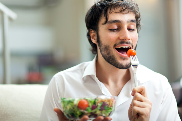 Young man eating a healthy salad - 写真・画像