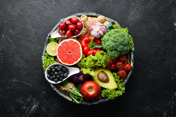 Fresh vegetables and fruits on a black background. Vitamins and minerals. Top view. Free space for your text. - Foto, Imagen
