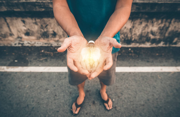 A man hold Light bulb in hands. - Foto, afbeelding