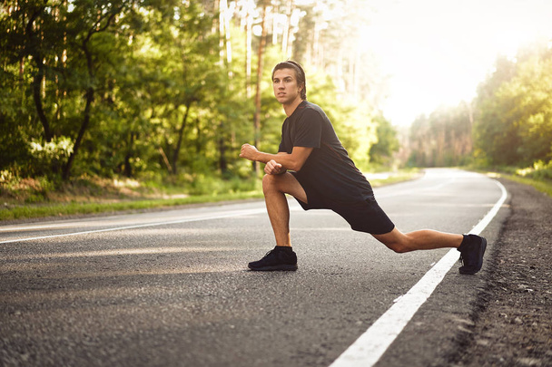 Middle age man warming up at forest road before jogging. Men stretching for running exercises. Handsome 30s athlet doing fitness outdoor  - Fotografie, Obrázek
