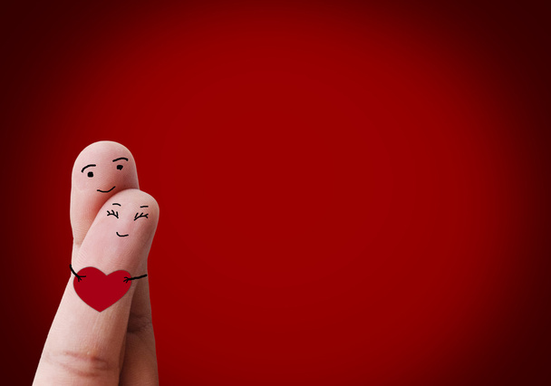 ευτυχισμένο ζευγάρι ερωτευμένος με ζωγραφισμένο γελαστά κρατώντας κόκκινη καρδιά - Φωτογραφία, εικόνα