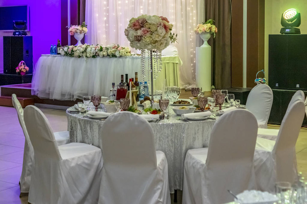 Tische und Stühle in Weiß auf Hochzeitsfeier im Restaurant dekoriert - Foto, Bild