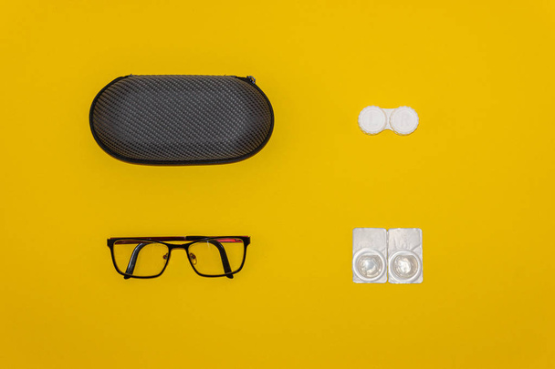Óculos, lentes de contato e kits de armazenamento em fundo amarelo
 - Foto, Imagem