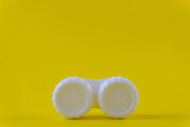 Розмитий футляр для зберігання контактних лінз на жовтому фоні
 - Фото, зображення