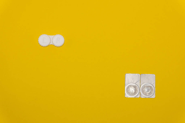 Soczewki kontaktowe i etui do przechowywania soczewek na żółtym tle - Zdjęcie, obraz
