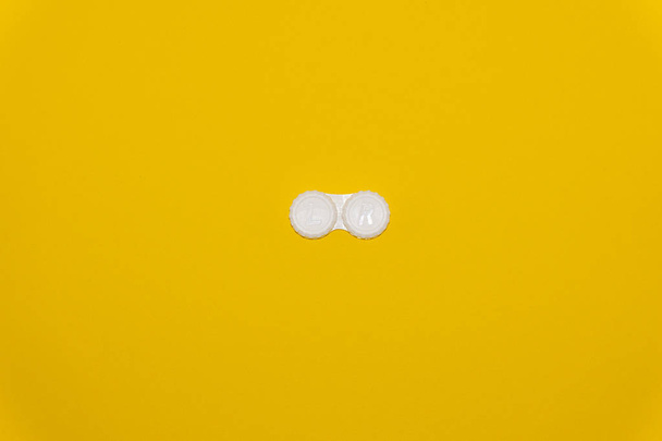 Piilolinssin säilytyskotelo keltaisella pohjalla
 - Valokuva, kuva