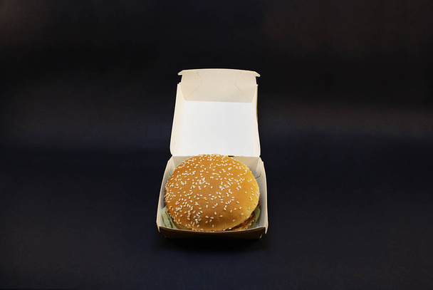 Schadelijke hamburger, Fast Food op een donkere achtergrond. - Foto, afbeelding