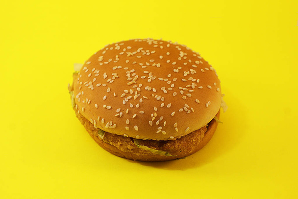 Schadelijke hamburger, Fast Food op een gele achtergrond. - Foto, afbeelding