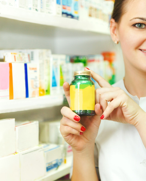 Close-up van een wazig vrouwelijke apotheker stak tabletten in bo - Foto, afbeelding