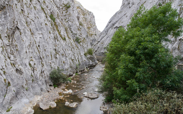 River and road with retaining walls on the edge, in a narrow gorge between stone mountains - Foto, Bild