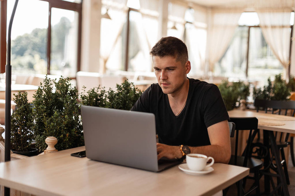 Smart homme réussi travaille sur un nouveau projet financier sur un ordinateur portable moderne tout en étant assis dans un café. Gestionnaire réussi attrayant travaillant à distance à l'intérieur. Temps de travail
 - Photo, image