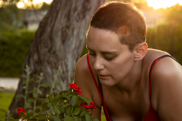 junge Frau riecht rote Blumen - Foto, Bild
