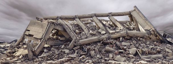 Eingestürztes Industriegebäude aus Beton mit dramatischem Himmel und ein weiteres Betongebäude im Hintergrund. Unglücksort voller Trümmer, Staub und beschädigtem Haus - Foto, Bild