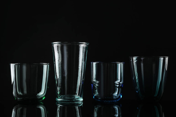 Set di diversi bicchieri vuoti colorati su sfondo nero
 - Foto, immagini