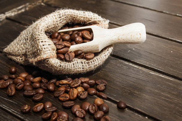 Granos de café en bolsa de cáñamo sobre un fondo de madera marrón
 - Foto, Imagen