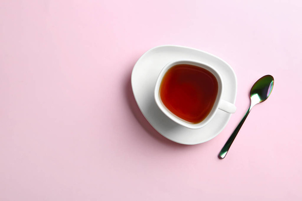 Cup of tea with saucer and spoon on pink background, flat lay. Space for text - Foto, Imagem