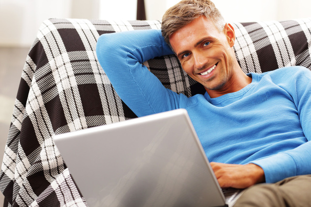 Handsome young man using laptop at home - Foto, Bild