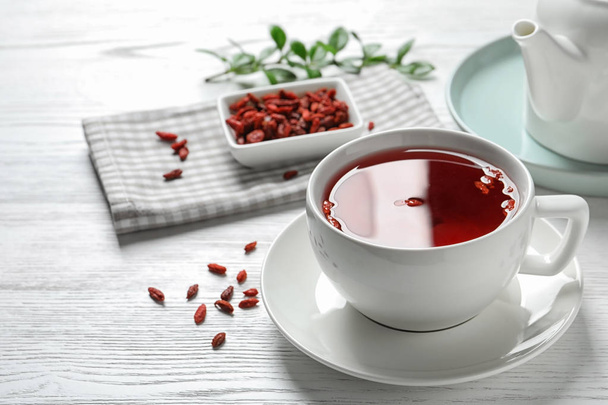 Healthy goji tea in cup on white wooden table - Foto, afbeelding