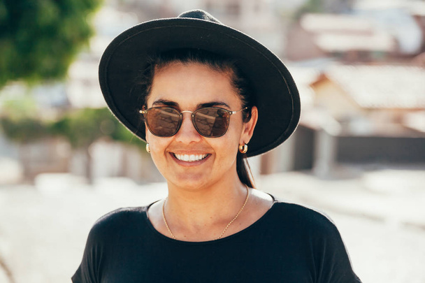 Close up portrait of a beautiful smiling girl with brown hair wearing a hat and looking at camera outdoors - Фото, изображение