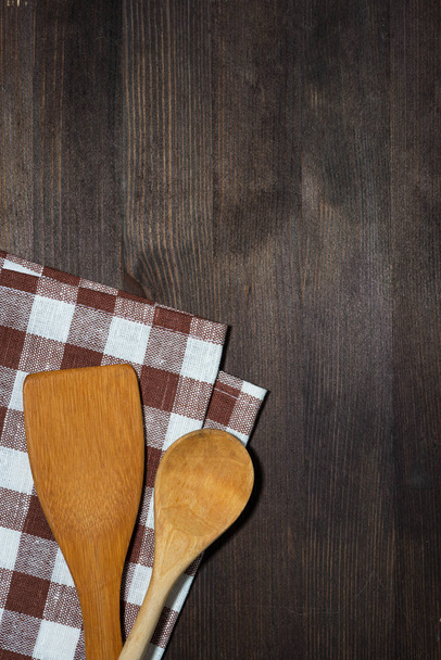 dishcloth, wooden spoons, wooden background, vertical top view - Foto, afbeelding