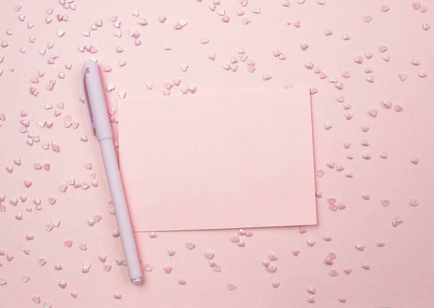 Pink sheet for writing and pen on a pink background and decorative hearts. Marriage proposal concept, Valentines Day, International Womens Day. Flat lay, top view - 写真・画像