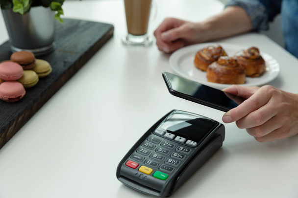Customer making wireless or contactless payment using smartphone - Foto, afbeelding