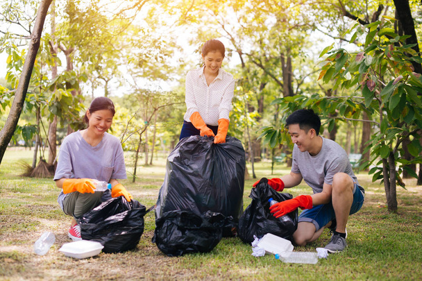 Young Asian people collecting trash in garbage bag in the park - Foto, imagen
