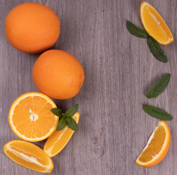 naranjas coloridas y fragantes en una mesa gris con menta brillante
. - Foto, imagen
