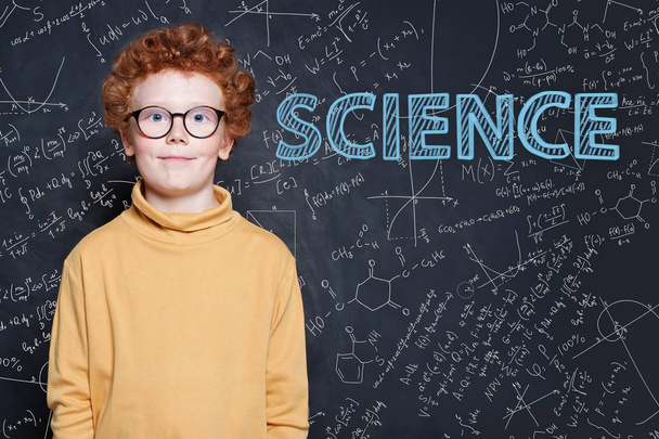 Smart kleiner Junge mit roten Ingwerhaaren auf wissenschaftlichem Hintergrund - Foto, Bild