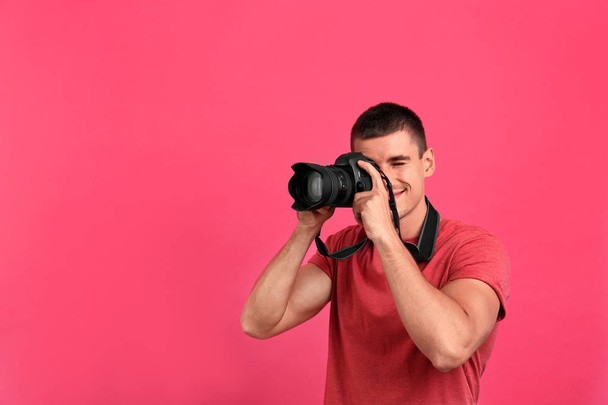 Young professional photographer taking picture on pink background. Space for text - Фото, зображення