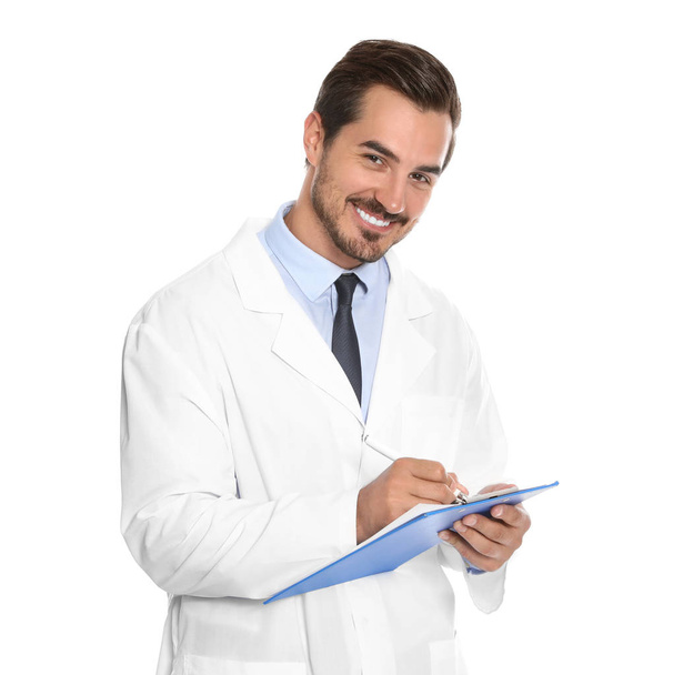 Young male doctor writing on clipboard against white background. Medical service - Foto, Imagen