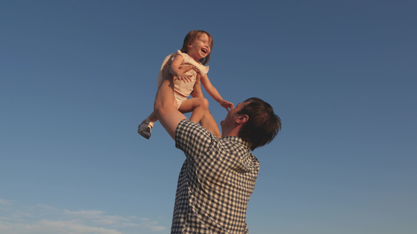 Dad throws up a happy daughter in the blue sky. Father and little child play, laugh and hug together. Happy family travels. Baby in the arms of the parent. Dad day off. The concept of a happy family. - Foto, Bild