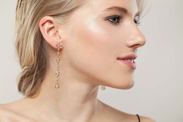 Closeup portrait of beautiful woman wearing golden earrings  - Photo, Image
