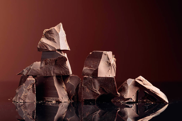 Pieces of dark chocolate on a dark background.  - Фото, изображение