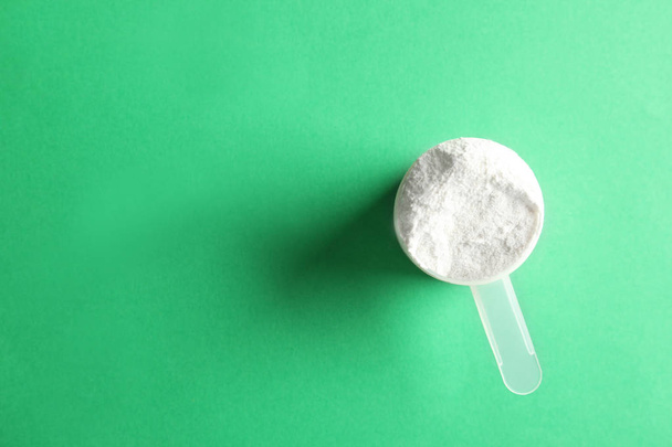 Scoop of protein powder on green background, top view with space for text - Valokuva, kuva