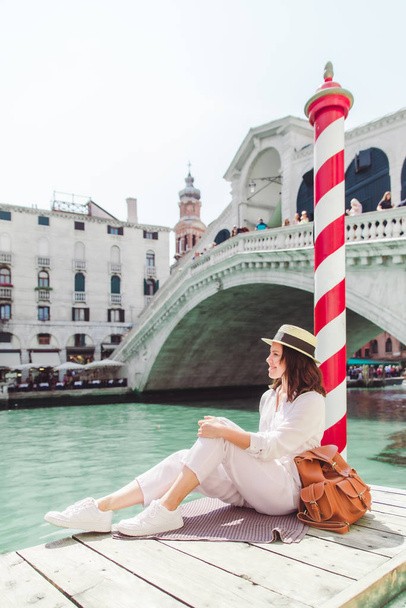 donna seduta vicino al ponte di Rialto a Venezia guardando il grande canale con le gondole
 - Foto, immagini