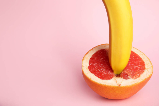 Fresh grapefruit and banana on pink background, space for text. Sex concept - Fotografie, Obrázek