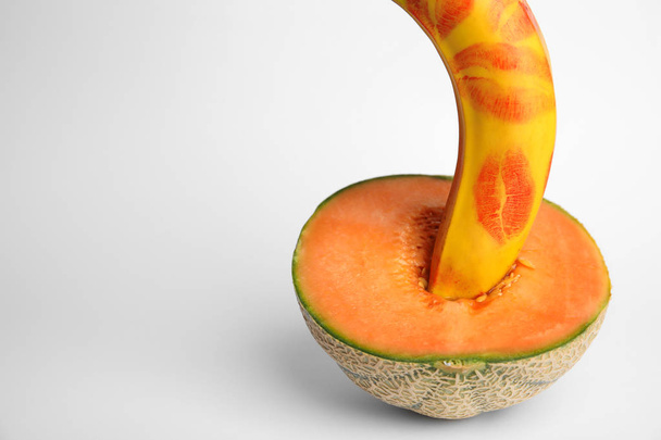 Fresh banana with red lipstick marks and melon on white background. Sex concept - Фото, изображение