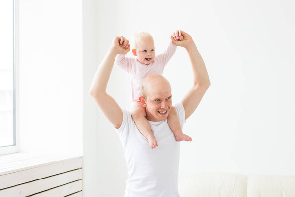 Отцовство и семейная концепция - отец и маленький ребенок малыша в помещении дома, играя
. - Фото, изображение
