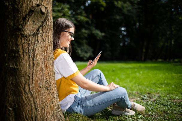 Student Girl Checking Smartphone in Park - Foto, afbeelding