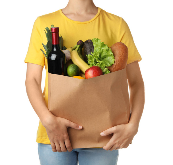 Woman holding shopping paper bag with different groceries on white background - Foto, afbeelding