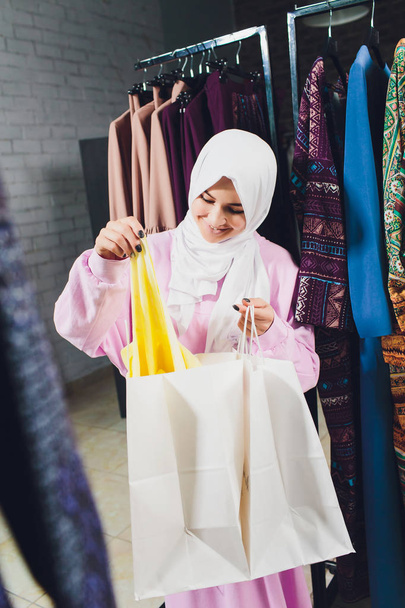 Arab woman in traditional Muslim clothes buys a new dress in an Oriental store. - Fotó, kép