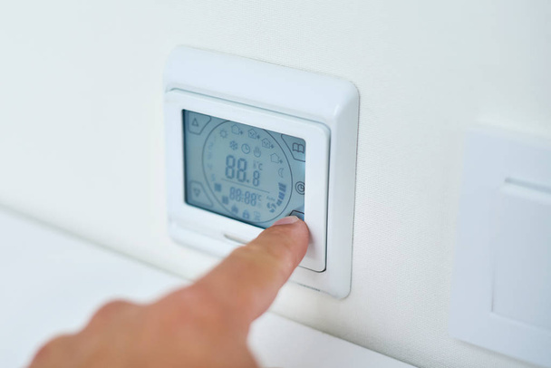 Temperatura de ajuste manual de los hombres en el panel de control de calefacción por suelo radiante
 - Foto, imagen