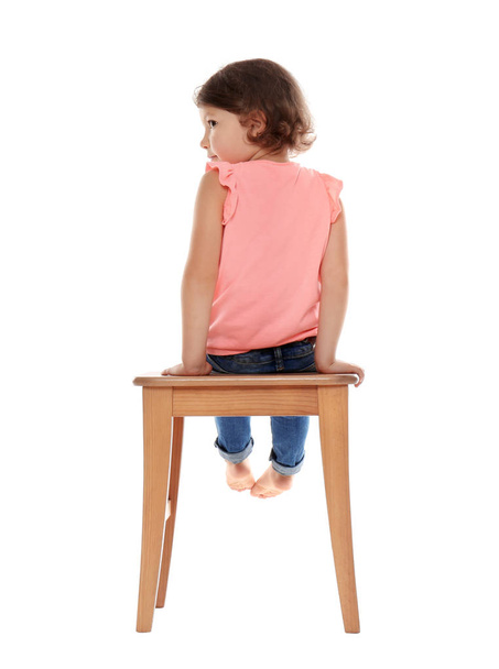 Little girl on stool against white background. Danger at home - Foto, afbeelding