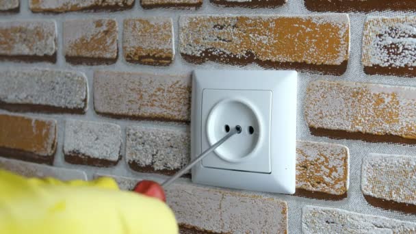 Menselijke hand in een rubberen handschoen installeert een socket op een bakstenen muur in het huis met een schroevendraaier. Selectieve focus. Close-up. - Video