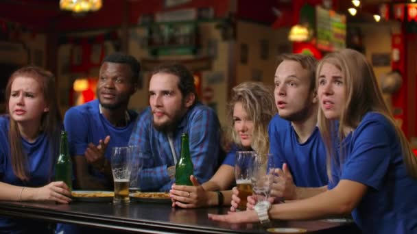 Emotionele fans in blauwe t-shirts aan de bierbar. Multi-etnische groep van Afro-Amerikaanse mensen zijn boos en verdrietig vanwege het falen van hun team. - Video