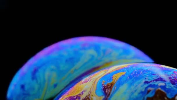 Macro shot of a soap bubble creates a colorful and black background - Footage, Video