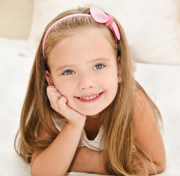 Smiling little girl resting on the bed - Foto, imagen